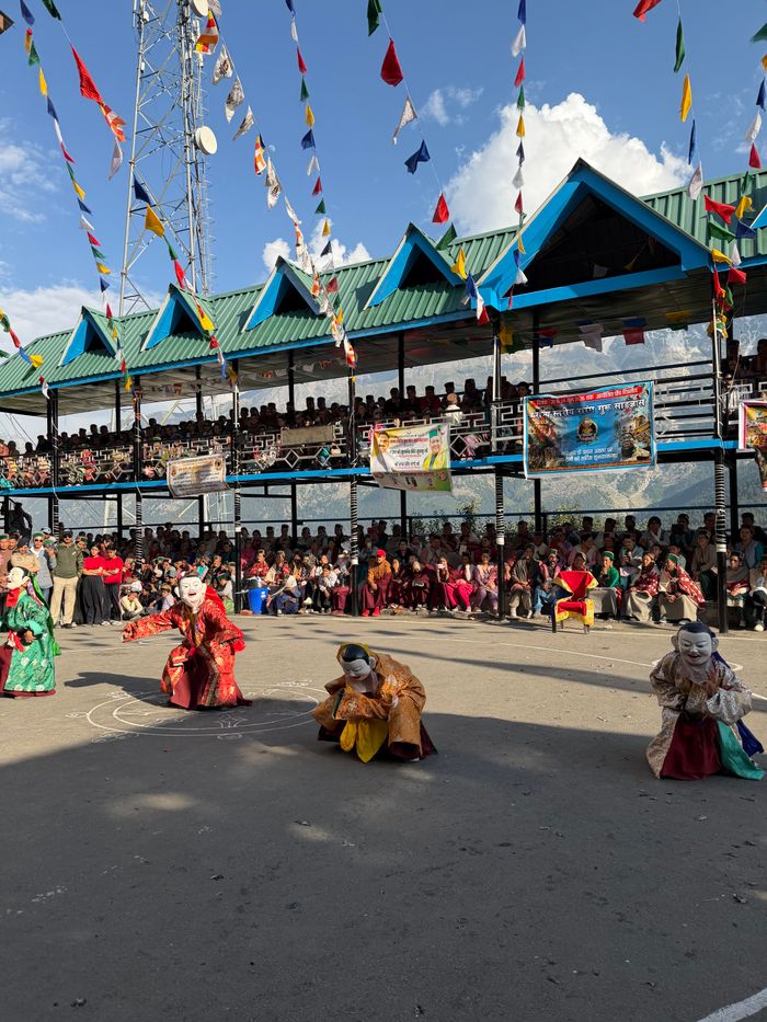 Vibrant cultural festival with masked dancers in Himachal Pradesh, India.